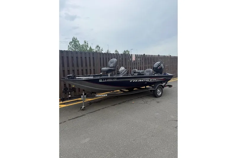 The Image of 2020 Tracker Pro Team 175 TF boat on trailer, parked near wooden fence. - 0