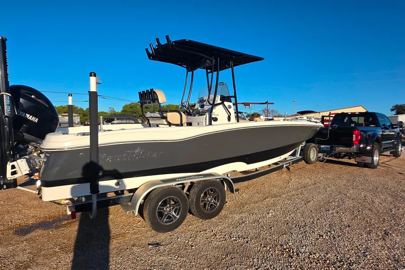 Slide: The Image of 2017 NauticStar 231 Angler boat on trailer, parked outdoors under clear blue sky. - 1