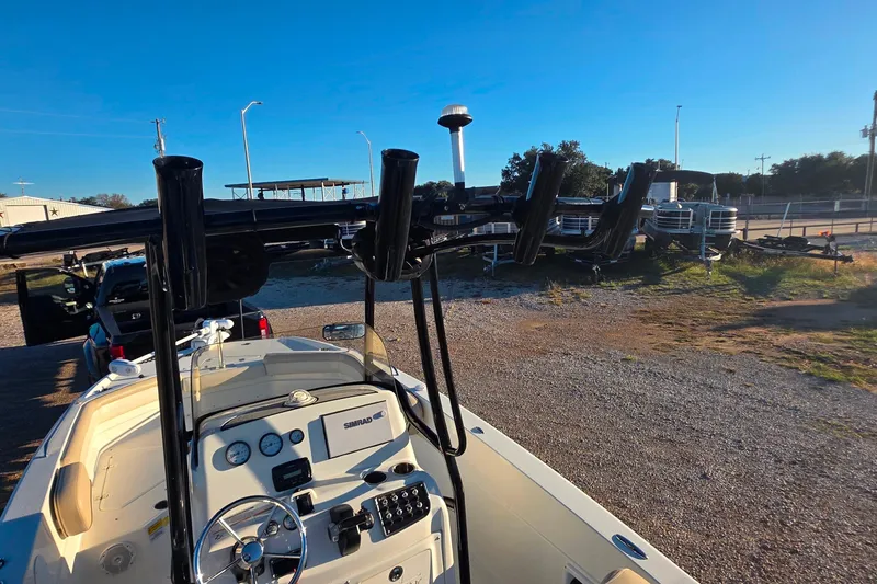 Slide: The Image of 2017 NauticStar 231 Angler boat with console and rod holders, parked outdoors. - 12