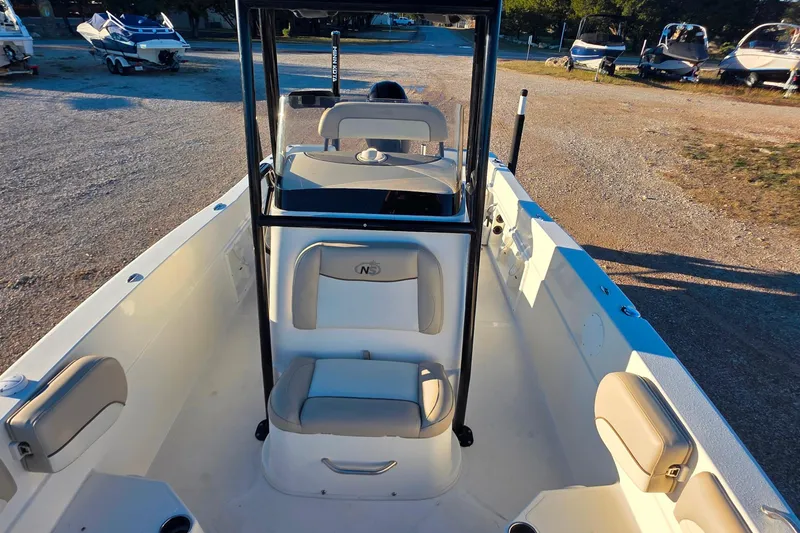 Slide: The Image of 2017 NauticStar 231 Angler boat interior with seating and console, parked on gravel. - 19