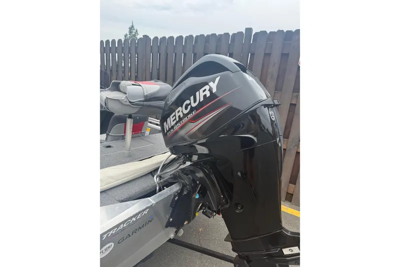 Slide: The Image of 2015 Tracker Pro 160 boat with Mercury outboard motor, parked near wooden fence. - 5