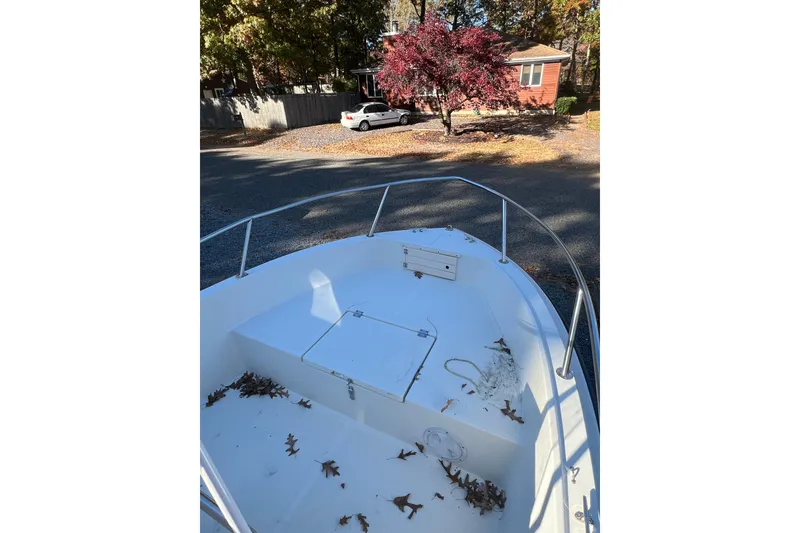 Slide: The Image of 1994 Stratos 1850 Center Console boat with leaves on deck, parked near a house. - 11