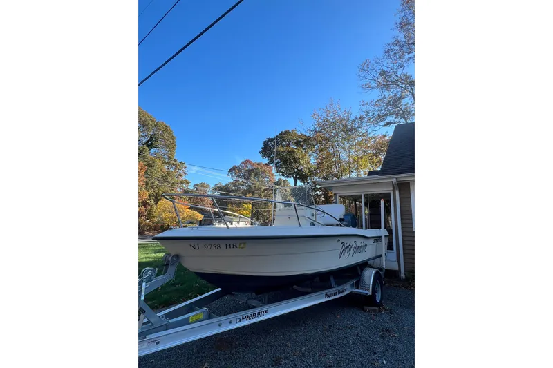 Slide: The Image of 1994 Stratos 1850 Center Console boat on trailer, parked beside a house under clear blue sky. - 3