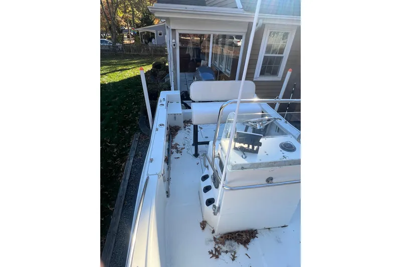 Slide: The Image of 1994 Stratos 1850 Center Console boat with leaves on deck, parked near a house. - 7