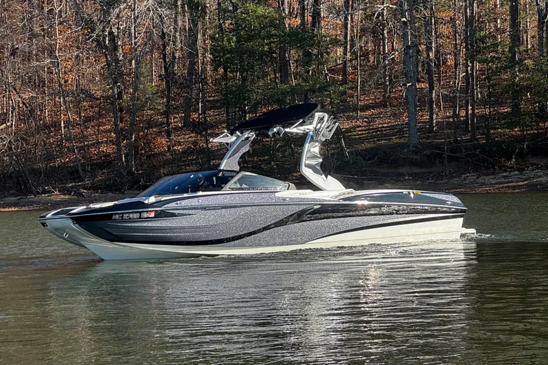 Slide: The Image of 2019 Centurion Fi25 boat cruising on a calm lake with forested background. - 12