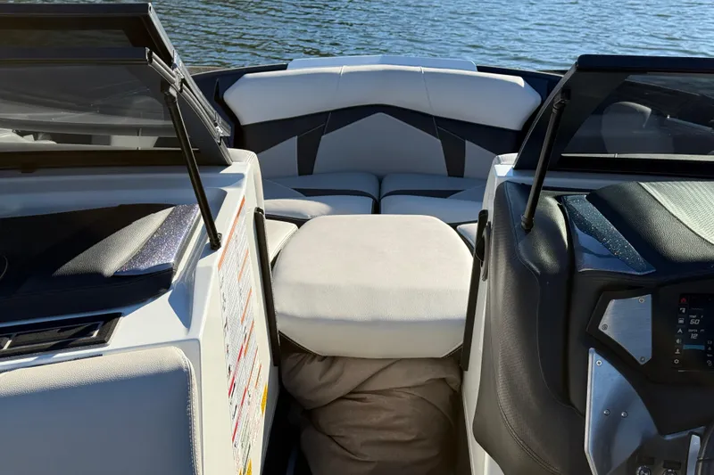 Slide: The Image of 2019 Centurion Fi25 boat interior with modern seating and dashboard, on a calm lake. - 14