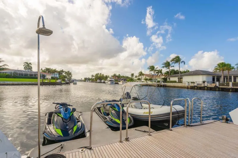 Slide: The Image of Docked jet skis and boat on a sunny waterfront with palm trees and houses. - 44
