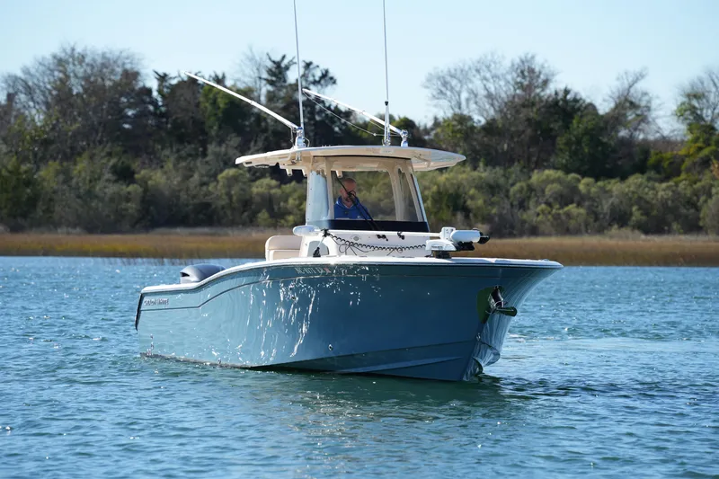 Slide: The Image of 2021 Grady-White Canyon 271 boat cruising on a serene lake with trees in the background. - 10