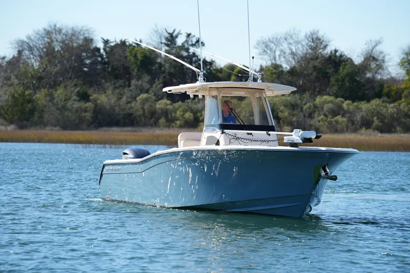 Slide: The Image of 2021 Grady-White Canyon 271 boat cruising on a serene lake with lush greenery. - 11