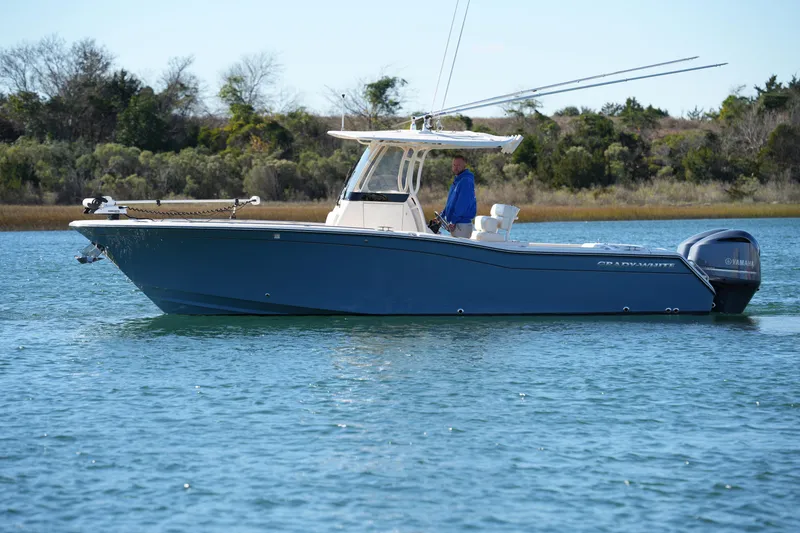 Slide: The Image of 2021 Grady-White Canyon 271 boat on calm water, side view with trees in background. - 17