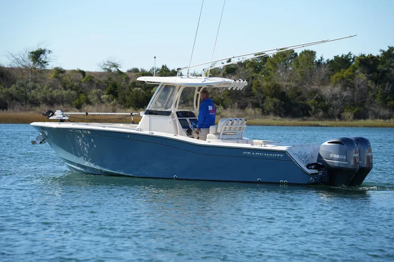 Slide: The Image of 2021 Grady-White Canyon 271 boat cruising on a calm lake with trees in the background. - 18