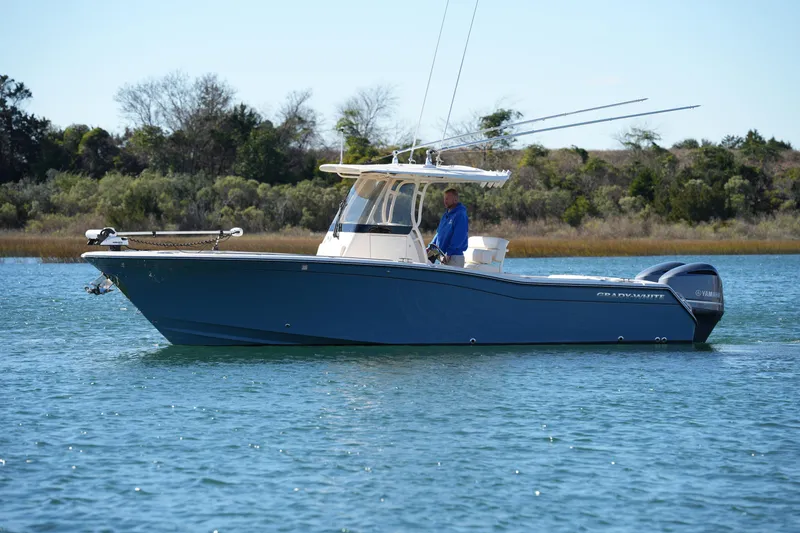 Slide: The Image of 2021 Grady-White Canyon 271 boat on calm water, featuring dual outboard engines. - 2