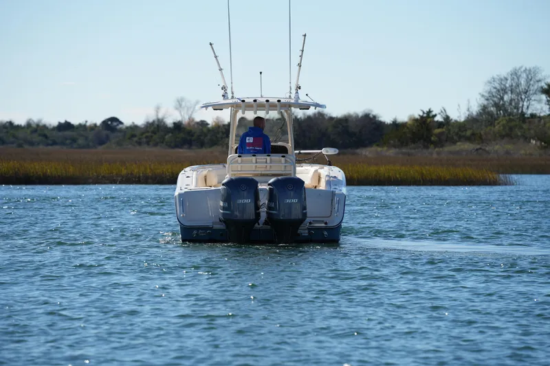Slide: The Image of 2021 Grady-White Canyon 271 boat cruising on a calm lake with scenic background. - 24