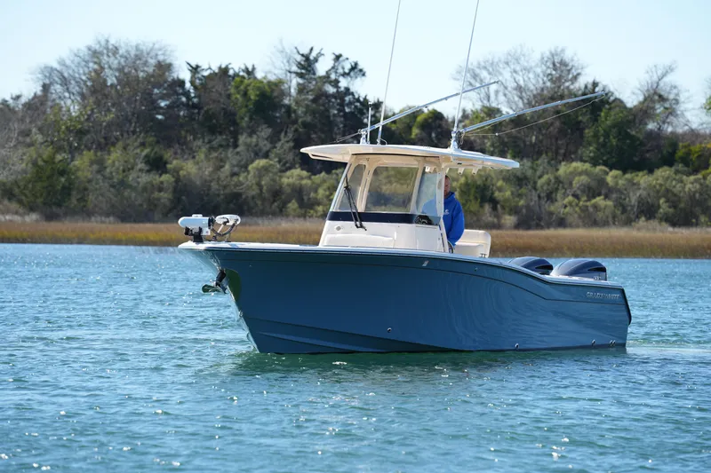 Slide: The Image of 2021 Grady-White Canyon 271 boat on calm water, surrounded by trees. - 3