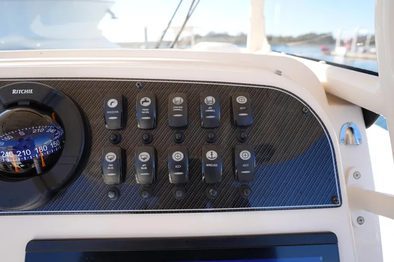 Slide: The Image of Control panel of 2021 Grady-White Canyon 271 boat with switches and compass. - 38