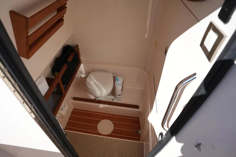Slide: The Image of 2021 Grady-White Canyon 271 boat interior with compact bathroom and wooden accents. - 45