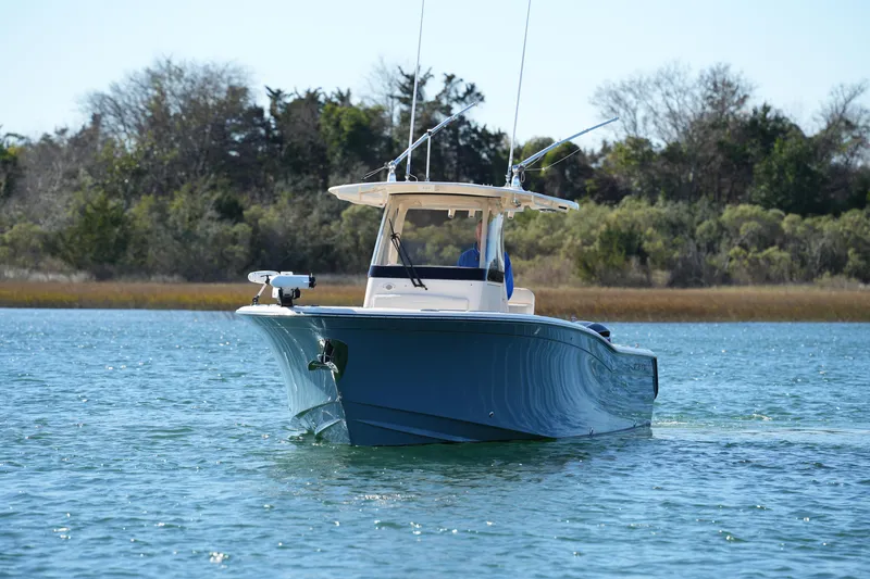Slide: The Image of 2021 Grady-White Canyon 271 boat cruising on a serene lake with trees in the background. - 5