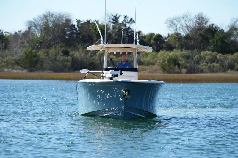 Slide: The Image of 2021 Grady-White Canyon 271 boat cruising on a serene lake with lush greenery. - 8