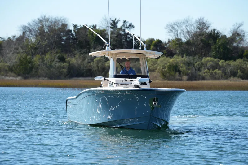 Slide: The Image of 2021 Grady-White Canyon 271 boat cruising on a serene lake with trees in the background. - 9