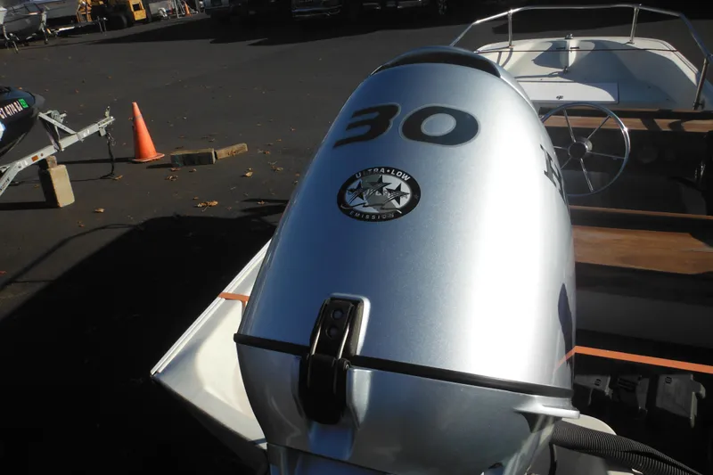 Slide: The Image of 1986 Boston Whaler 13 boat with a 30 HP outboard motor in a parking lot. - 10