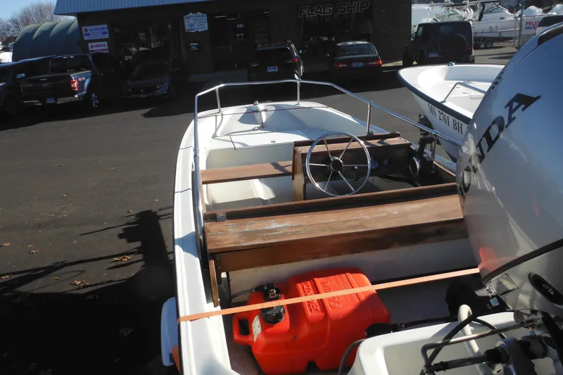 Slide: The Image of 1986 Boston Whaler 13 boat with Honda outboard motor and fuel tank, parked outdoors. - 6