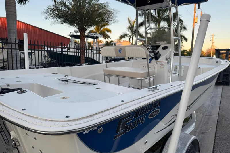 Slide: The Image of 2016 Carolina Skiff 198 DLV boat with center console, parked near palm trees. - 8