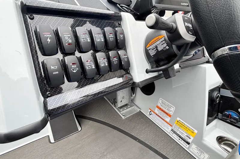 Slide: The Image of Control panel of 2026 Triton 20XP Patriot boat with labeled switches and steering wheel. - 12