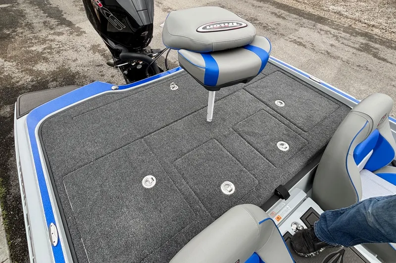 Slide: The Image of 2026 Triton 20XP Patriot boat deck with gray carpet and blue-accented seating. - 15