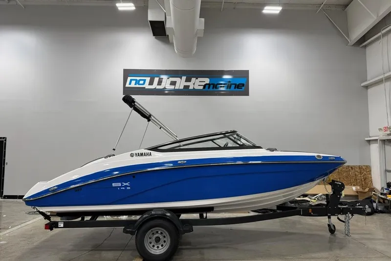 The Image of 2025 Yamaha Boats SX195 in showroom, blue and white design, on trailer. - 0