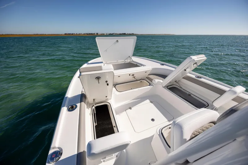Slide: The Image of 2026 Caymas 26 HB boat interior with open storage compartments on calm water. - 11