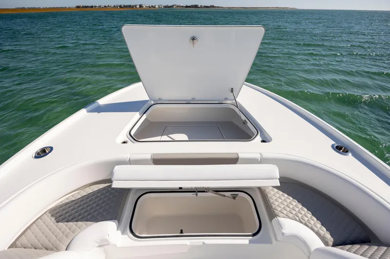 Slide: The Image of 2026 Caymas 26 HB boat with open storage compartments on calm water. - 14