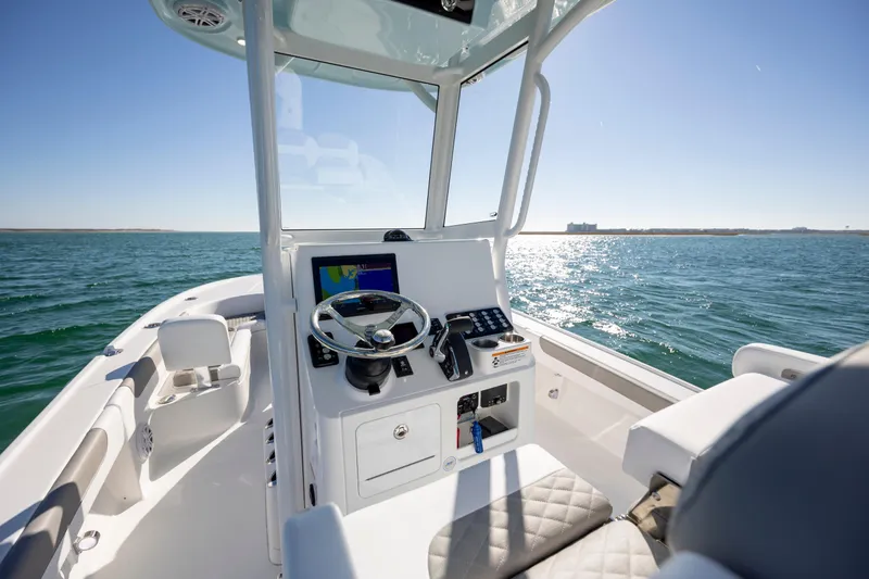 Slide: The Image of 2026 Caymas 26 HB boat interior with steering wheel, dashboard, and ocean view. - 17