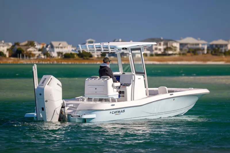 Slide: The Image of 2026 Caymas 26 HB boat cruising on clear waters near a coastal town. - 2
