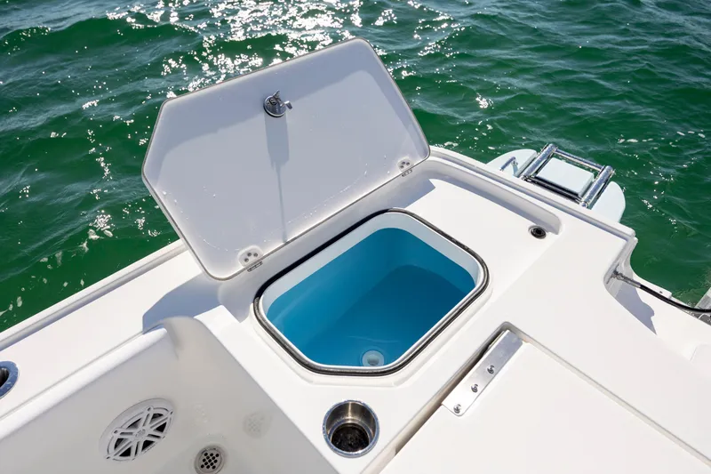 Slide: The Image of 2026 Caymas 26 HB boat with open storage compartment on deck, near water. - 25