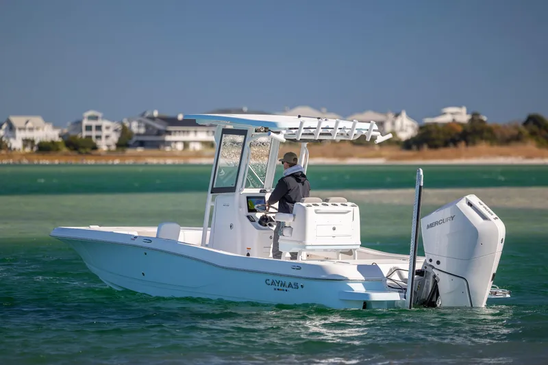 Slide: The Image of 2026 Caymas 26 HB boat cruising on turquoise waters near coastal homes. - 4