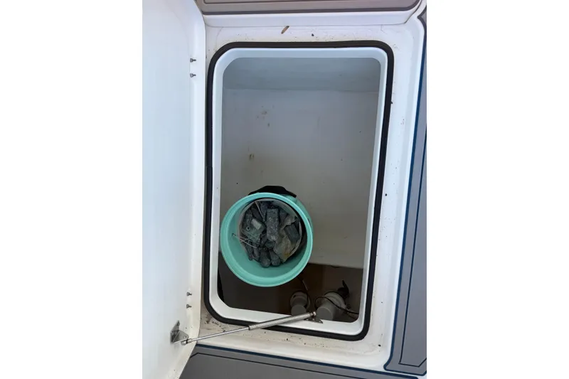 Slide: The Image of Open storage compartment on 2013 Freeman 33 boat with bucket and items inside. - 77