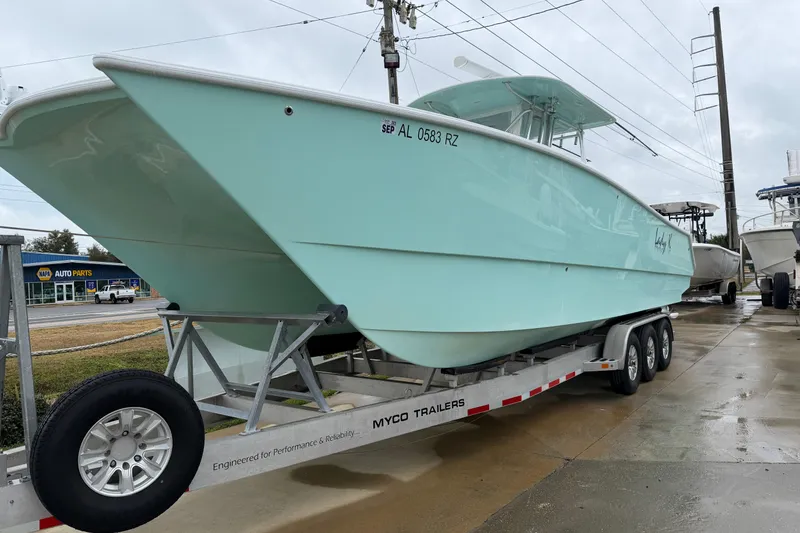 Slide: The Image of 2013 Freeman 33 boat on trailer, light blue hull, parked near auto parts store. - 81