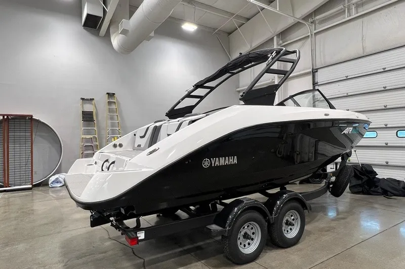 Slide: The Image of 2025 Yamaha Boats AR220 in a showroom, sleek black and white design on a trailer. - 2