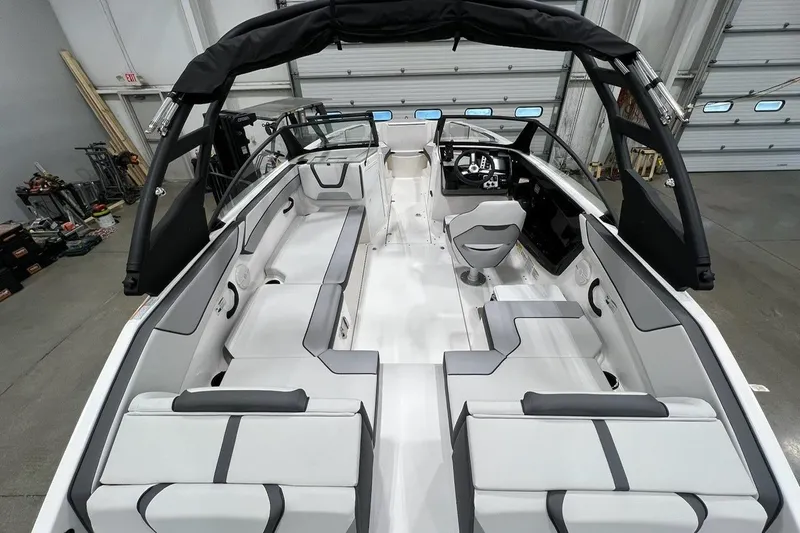 Slide: The Image of 2025 Yamaha Boats AR220 interior with sleek seating and modern dashboard in a showroom. - 4