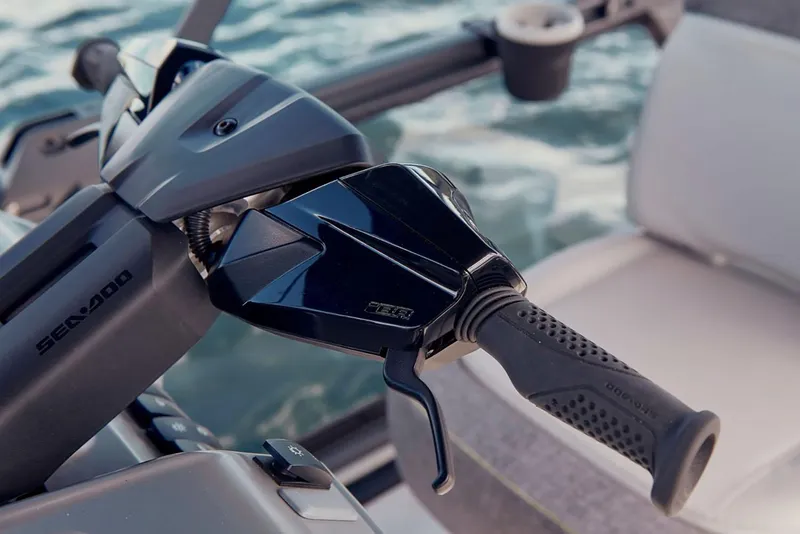 Slide: The Image of Manufacturer Provided Image: 2026 Sea-Doo Switch 16 handlebar with throttle control, set against a water backdrop. - 2