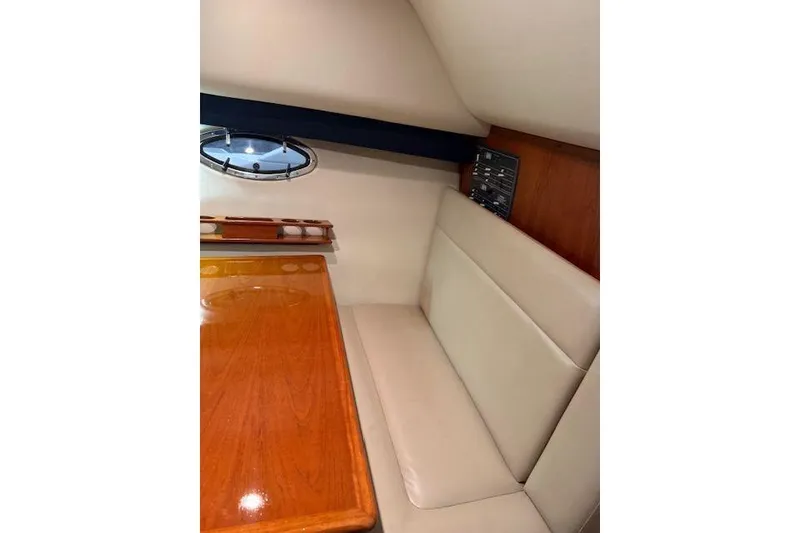 Slide: The Image of 1997 Tiara Yachts 2900 Open cabin interior with beige seating and wooden table. - 27