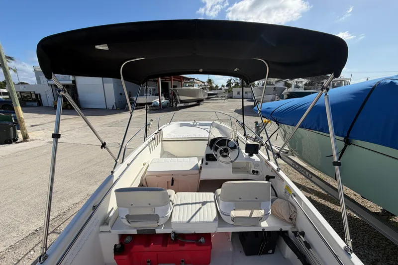 Slide: The Image of 2018 Boston Whaler 170 Super Sport boat with canopy, docked at marina. - 11