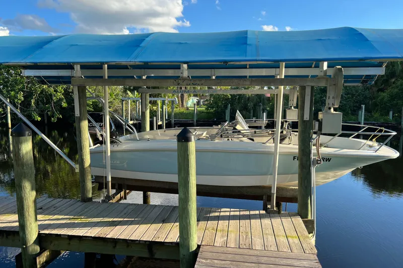 Slide: The Image of 2018 Boston Whaler 170 Super Sport boat with canopy, parked near white fence. - 3