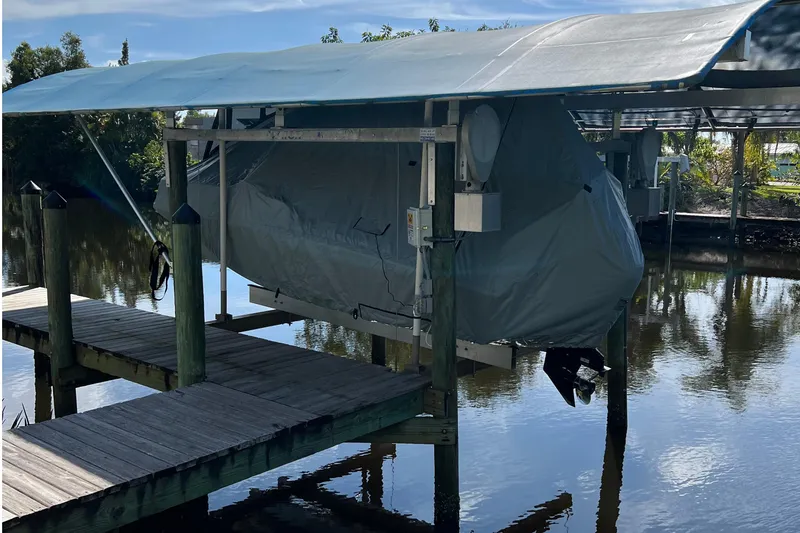 Slide: The Image of 2018 Boston Whaler 170 Super Sport boat in a marina, featuring rod holders and cushioned seating. - 5