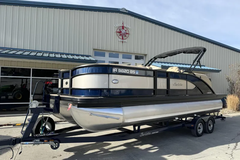 Slide: The Image of 2019 Barletta L23QC SS pontoon boat on trailer outside a marine dealership. - 1