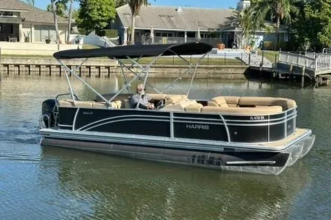 Slide: The Image of 2017 Harris Cruiser 220 pontoon boat on a calm waterway, featuring a sleek black design. - 14