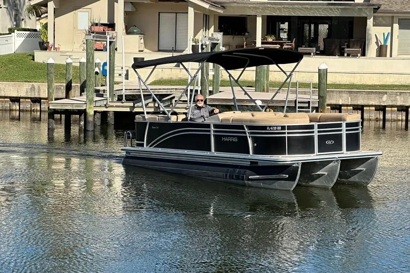 Slide: The Image of 2017 Harris Cruiser 220 pontoon boat on calm water near a dock. - 16