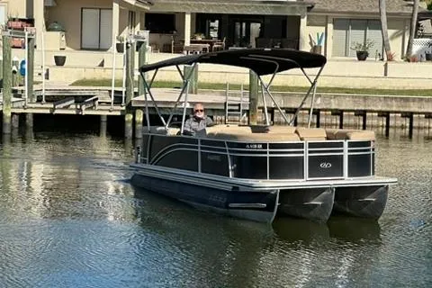 Slide: The Image of 2017 Harris Cruiser 220 pontoon boat navigating a calm residential waterway. - 17