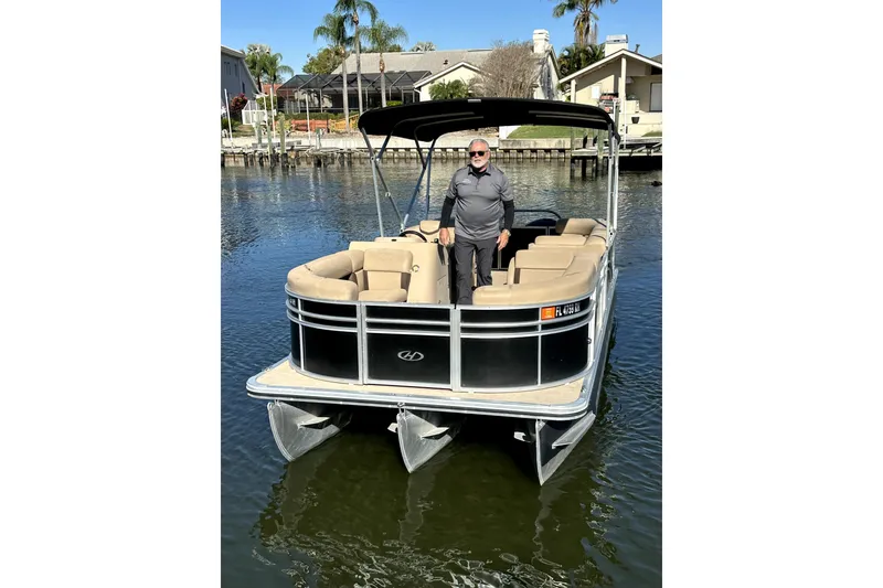 Slide: The Image of 2017 Harris Cruiser 220 pontoon boat on water with a person standing onboard. - 19