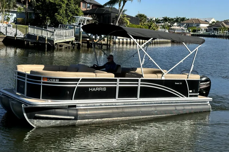 Slide: The Image of 2017 Harris Cruiser 220 pontoon boat on a calm waterway with canopy and seating. - 2